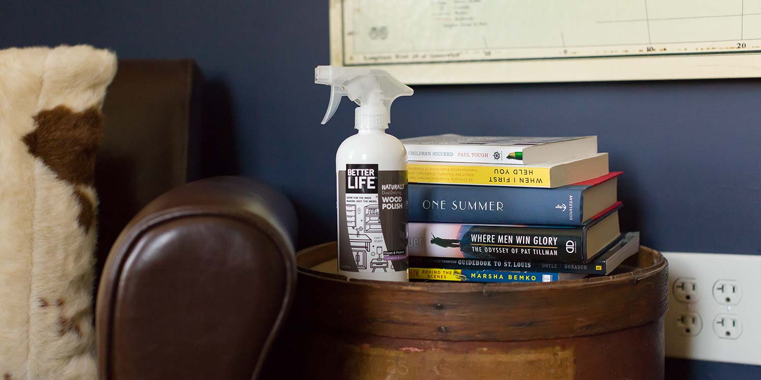 A picture of Better Life's Wood Polish sitting on a counter with some books and a chair near it