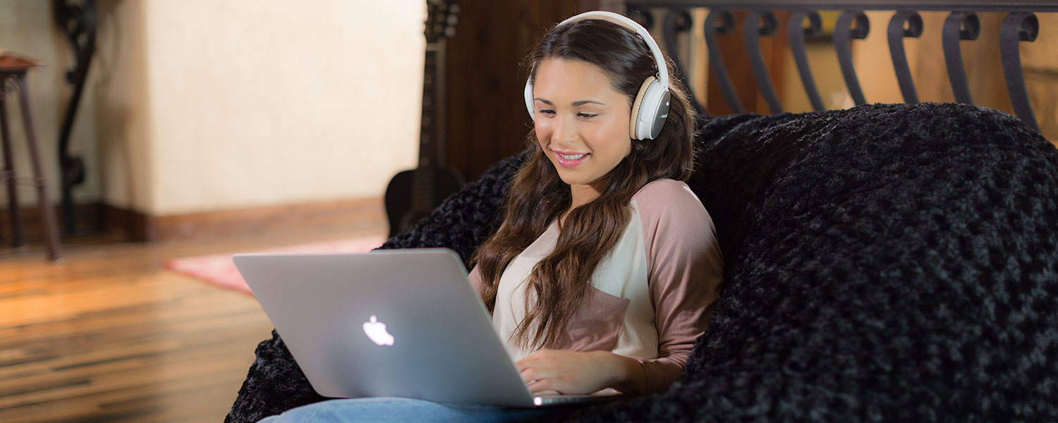 A woman sitting comfortably on a Comfy Sack with a computer on her lap