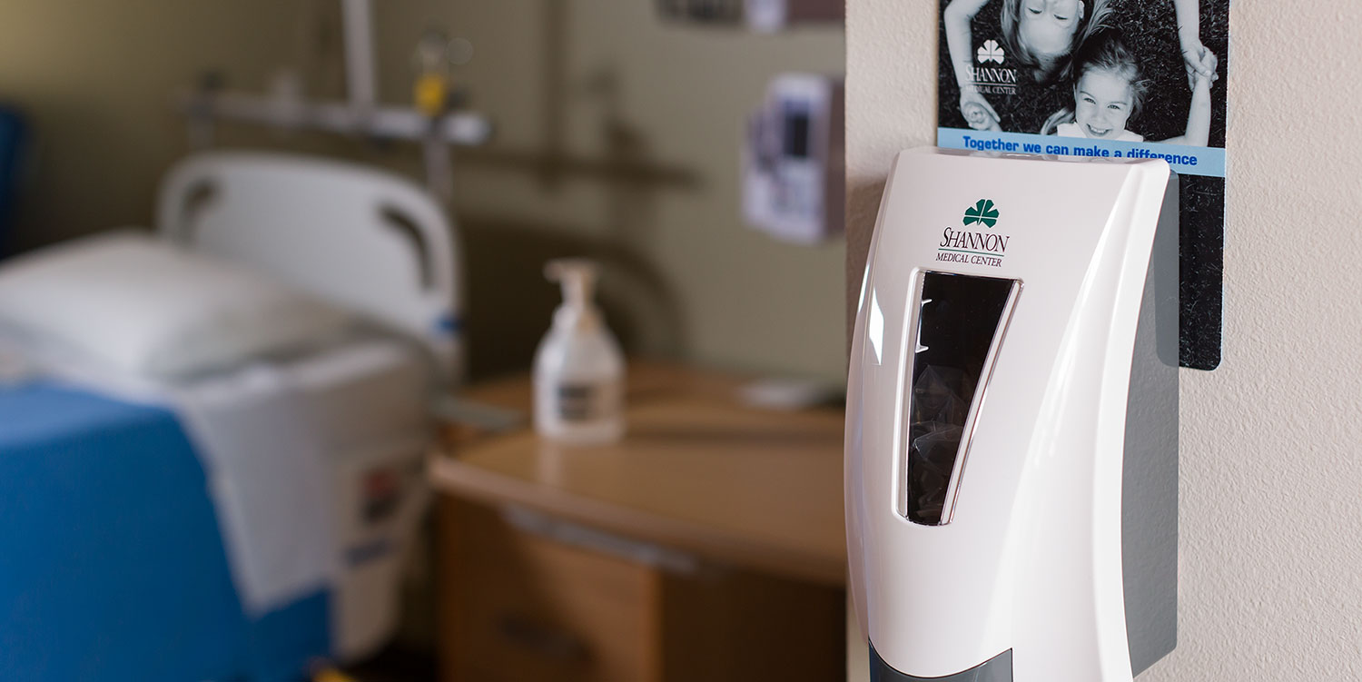 An image of Symmetry dispenser on the wall in a hospital along with Symmetry hand soap on the counter