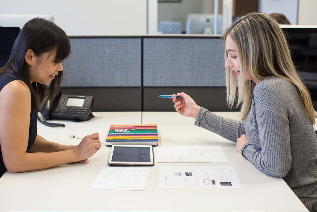 An image of Chrissy and Ling, of the Loft, going over branding material for a client